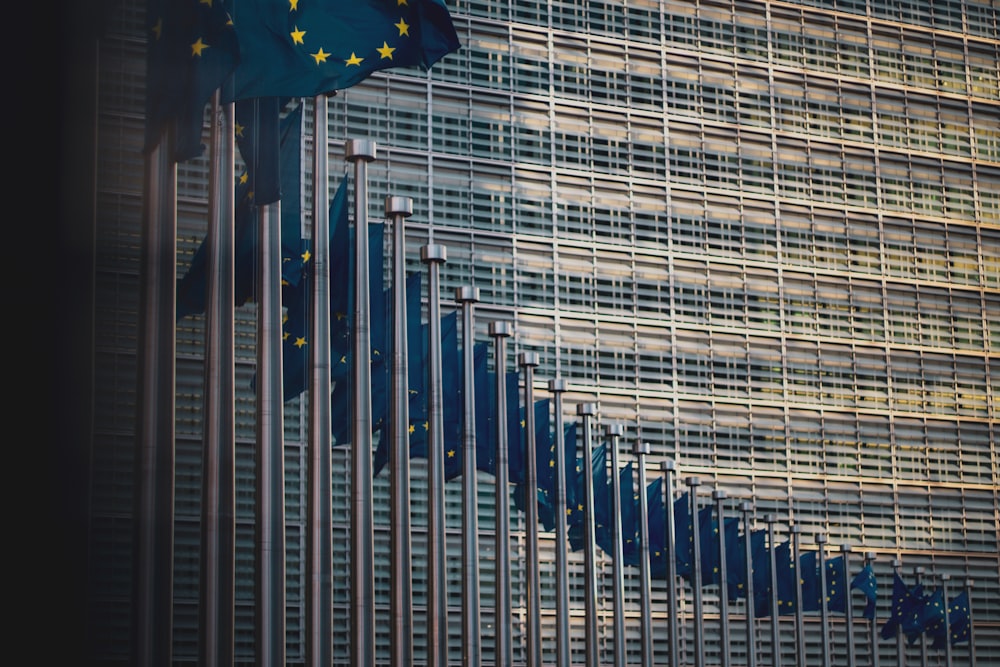 Eine Reihe von Europaflaggen vor dem Gebäude der Europäischen Kommission.
